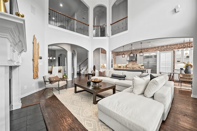 living room with a towering ceiling, dark hardwood / wood-style floors, and a notable chandelier