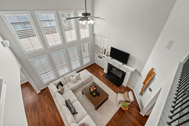 living room with a high ceiling, dark hardwood / wood-style flooring, and ceiling fan