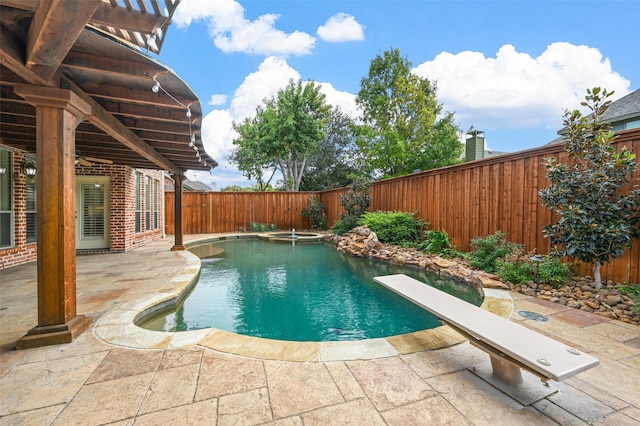 view of swimming pool featuring a patio and a diving board