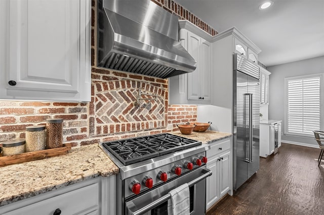 kitchen with white cabinetry, dark hardwood / wood-style flooring, premium appliances, and range hood