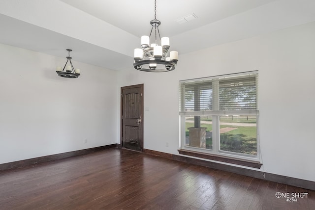 empty room featuring a notable chandelier and dark hardwood / wood-style floors