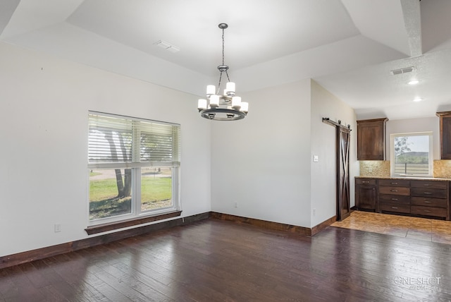 unfurnished dining area with dark hardwood / wood-style flooring, a barn door, and a healthy amount of sunlight