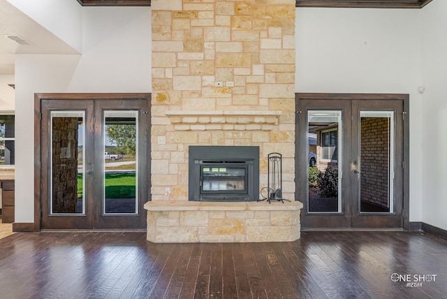 unfurnished living room with dark wood-type flooring, a fireplace, crown molding, and french doors