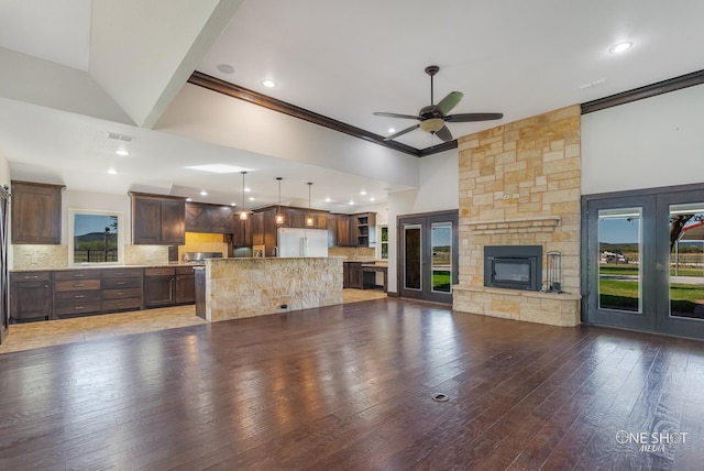 unfurnished living room with dark wood-type flooring, high vaulted ceiling, a stone fireplace, and ceiling fan