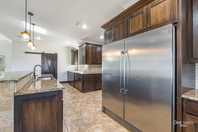 560 County Road 332, Abilene, TX 79606 - kitchen featuring stainless steel built in refrigerator, a barn door, a sink, dark stone countertops, and tasteful backsplash