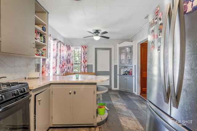 kitchen with black stove, ceiling fan, stainless steel fridge, tasteful backsplash, and kitchen peninsula