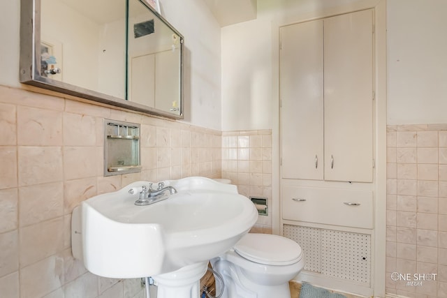 bathroom featuring toilet and tile walls