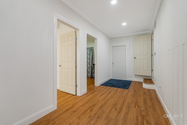 corridor with light wood-type flooring and crown molding