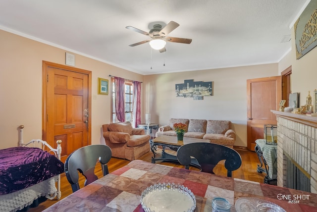 dining space featuring ornamental molding, hardwood / wood-style floors, ceiling fan, and a fireplace