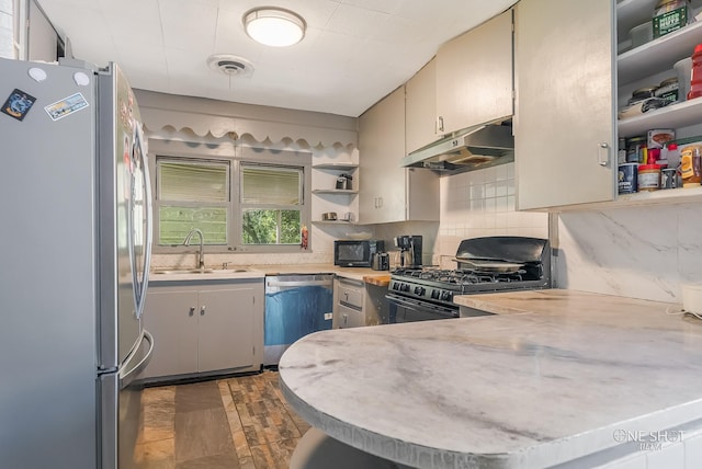 kitchen featuring kitchen peninsula, sink, backsplash, and black appliances