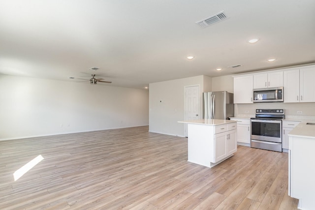 kitchen featuring ceiling fan, light wood-type flooring, a kitchen island, white cabinetry, and stainless steel appliances