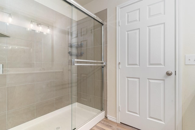 bathroom featuring a shower with shower door and hardwood / wood-style flooring