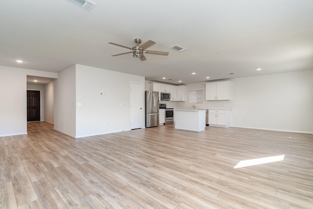 unfurnished living room with light hardwood / wood-style flooring, ceiling fan, and sink