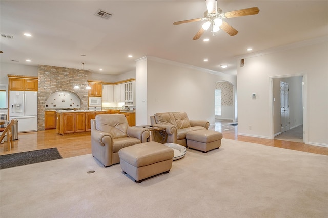 living room featuring ornamental molding, ceiling fan with notable chandelier, and light hardwood / wood-style floors