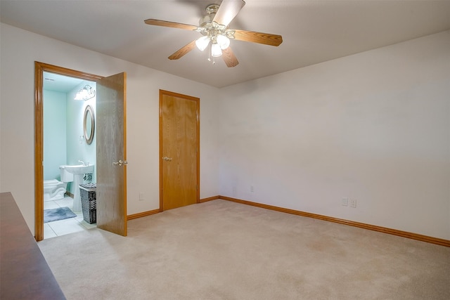 unfurnished bedroom featuring ceiling fan, ensuite bath, and light colored carpet