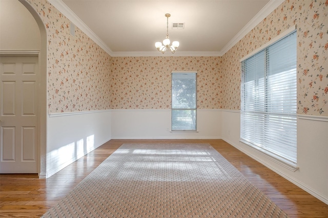 spare room featuring an inviting chandelier, hardwood / wood-style floors, and ornamental molding