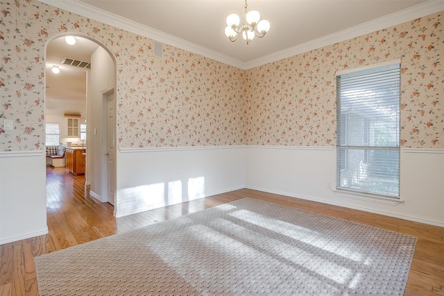 empty room with light hardwood / wood-style floors, a chandelier, and crown molding