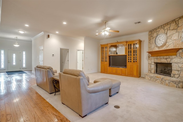 living room featuring ornamental molding, a fireplace, light hardwood / wood-style flooring, and ceiling fan