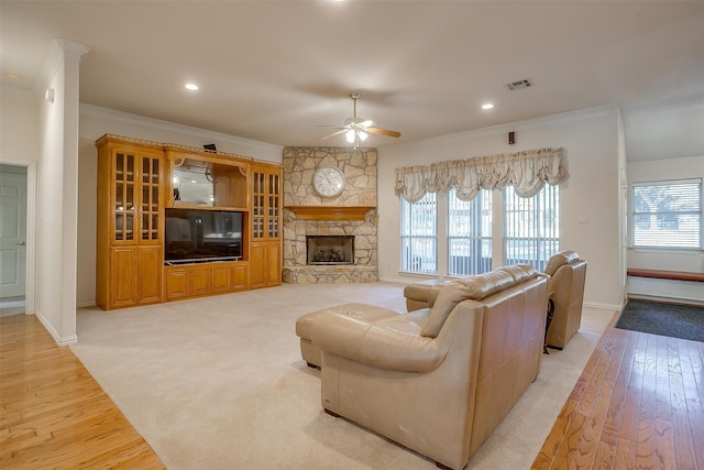 living room featuring a fireplace, a wealth of natural light, ceiling fan, and light hardwood / wood-style flooring