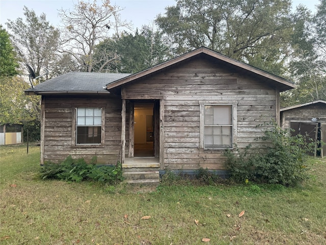 bungalow-style home featuring an outbuilding and a front lawn