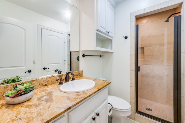 bathroom with toilet, vanity, and a shower with shower door