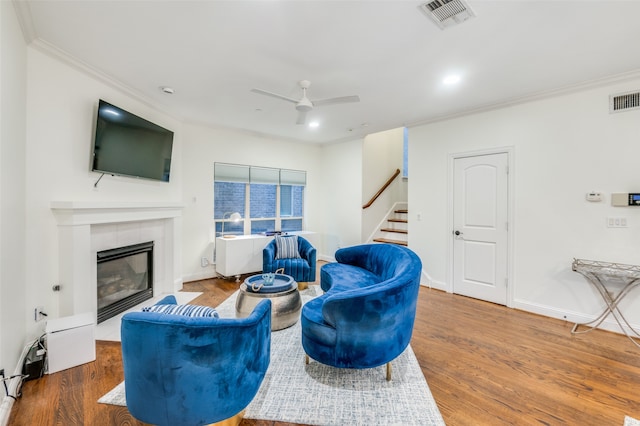 living room featuring a fireplace, ceiling fan, ornamental molding, and hardwood / wood-style floors