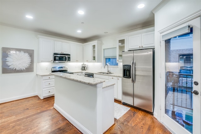 kitchen featuring stainless steel appliances, sink, dark hardwood / wood-style floors, a kitchen island, and white cabinetry