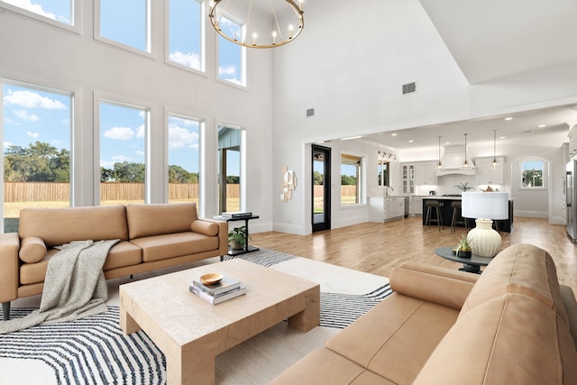 living room featuring plenty of natural light, light hardwood / wood-style floors, and a high ceiling