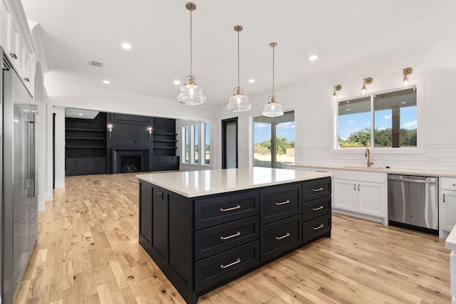 kitchen featuring stainless steel appliances, light hardwood / wood-style floors, white cabinets, a kitchen island, and decorative light fixtures