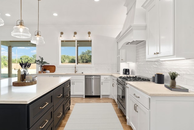 kitchen featuring pendant lighting, custom range hood, stainless steel appliances, and white cabinets