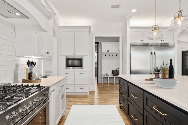 kitchen with built in appliances, crown molding, white cabinetry, light wood-type flooring, and decorative light fixtures