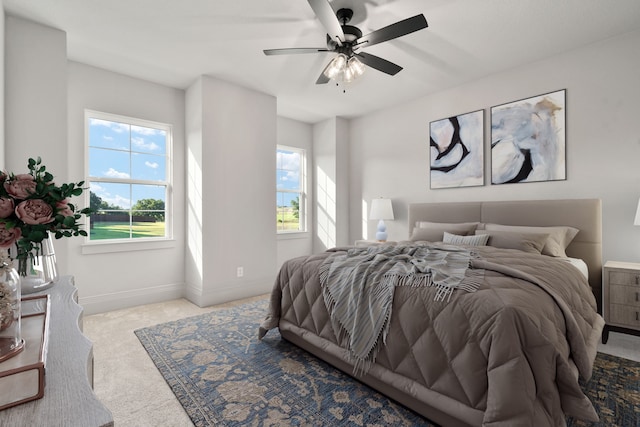 bedroom featuring multiple windows, light carpet, and ceiling fan