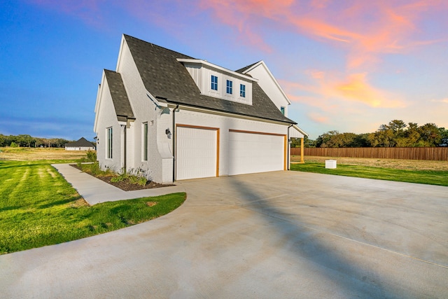 property exterior at dusk with a garage and a yard