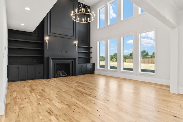 unfurnished living room featuring built in shelves, light hardwood / wood-style floors, and plenty of natural light