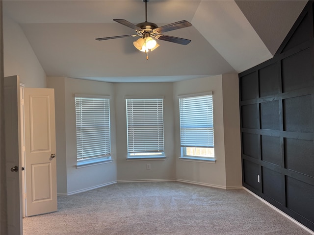 carpeted spare room featuring ceiling fan and vaulted ceiling