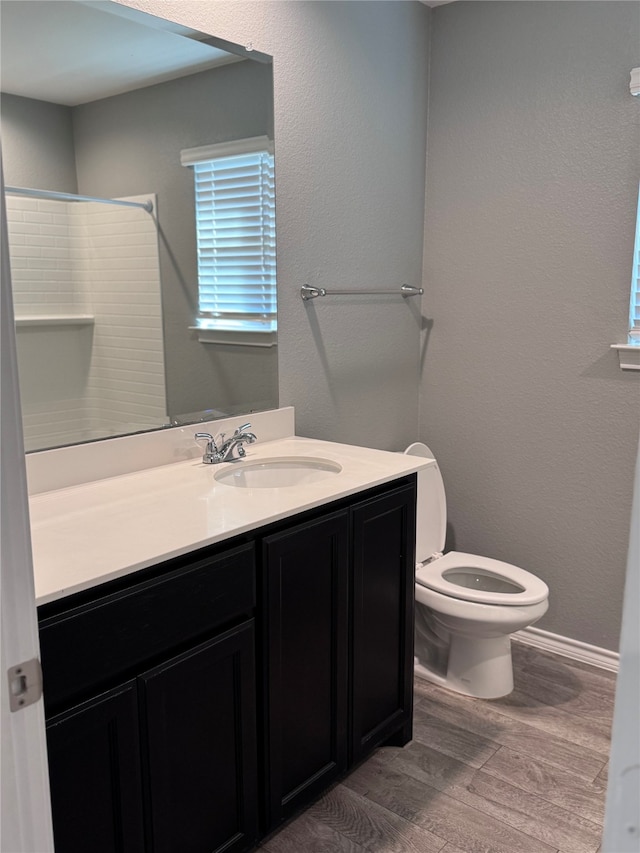 bathroom with a shower, vanity, wood-type flooring, and toilet