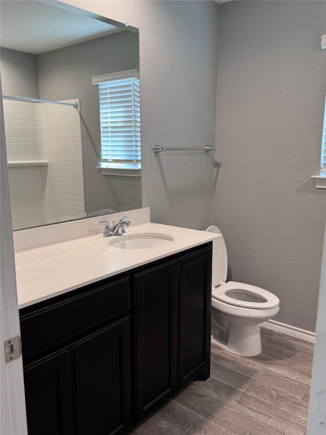 bathroom with hardwood / wood-style flooring, vanity, toilet, and walk in shower