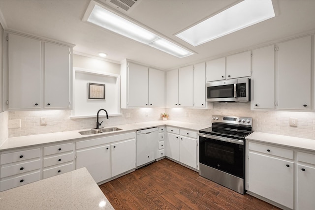 kitchen with appliances with stainless steel finishes, dark hardwood / wood-style floors, and white cabinets