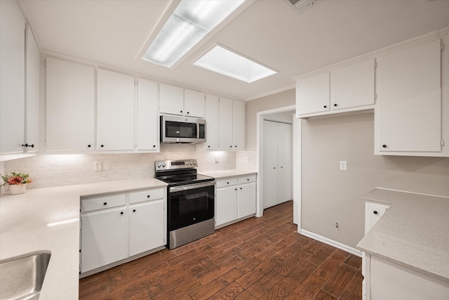 kitchen with white cabinets, dark hardwood / wood-style flooring, backsplash, and appliances with stainless steel finishes