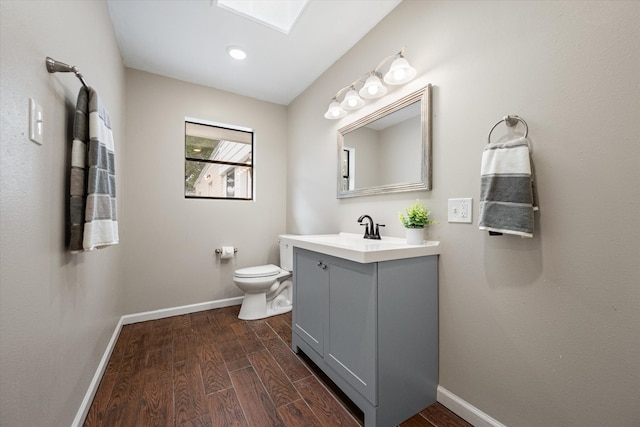 bathroom featuring vanity, hardwood / wood-style flooring, toilet, and a skylight