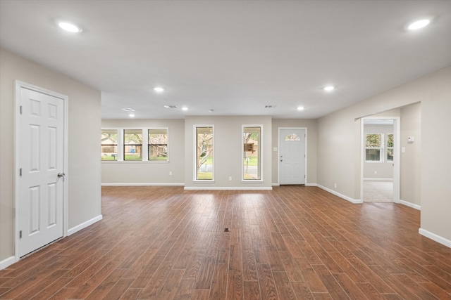 unfurnished living room featuring dark wood-type flooring and a healthy amount of sunlight