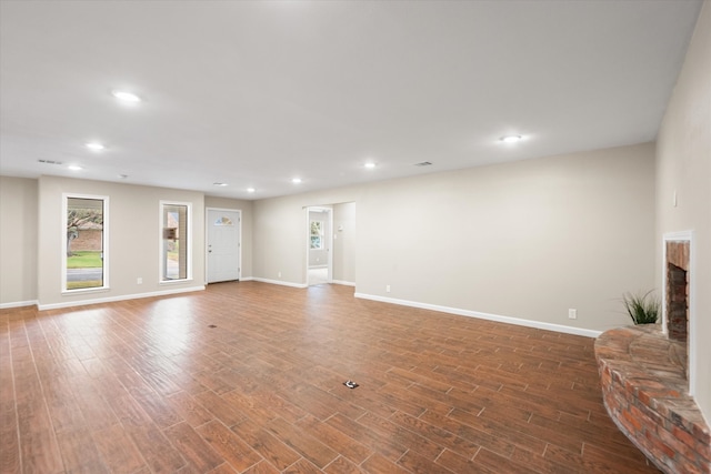 unfurnished living room with dark wood-type flooring and a fireplace