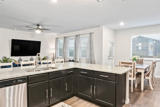 kitchen featuring sink, light hardwood / wood-style flooring, stainless steel dishwasher, and light stone countertops