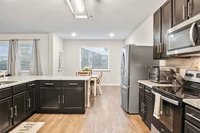 kitchen featuring light hardwood / wood-style floors, sink, tasteful backsplash, light stone countertops, and appliances with stainless steel finishes