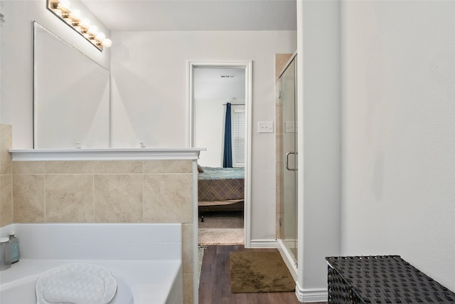 bathroom with wood-type flooring and shower with separate bathtub