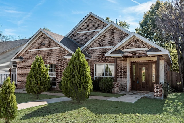 view of front of home featuring roof with shingles, brick siding, and a front lawn