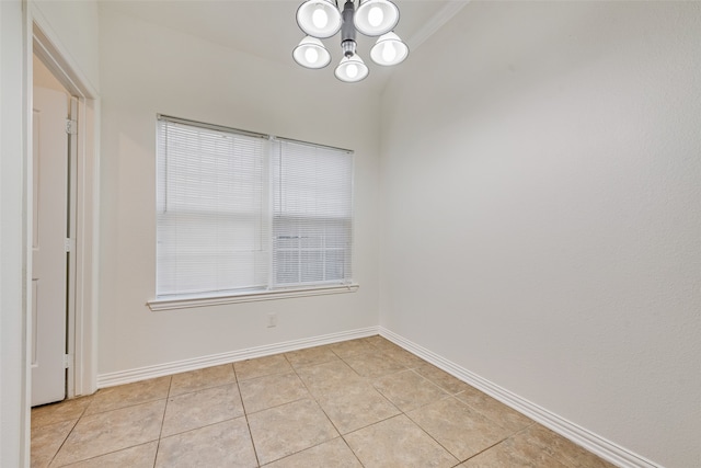 tiled spare room with a notable chandelier