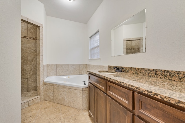 bathroom featuring tile patterned flooring, vanity, and tiled tub