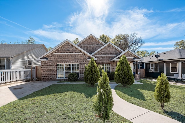 view of front of house with brick siding, fence, and a front lawn