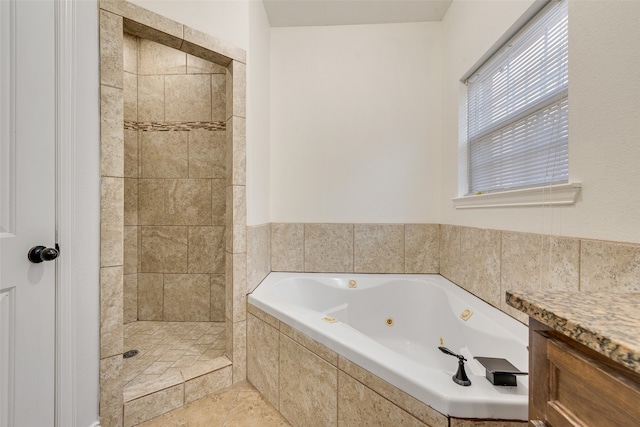 bathroom with vanity and a relaxing tiled tub